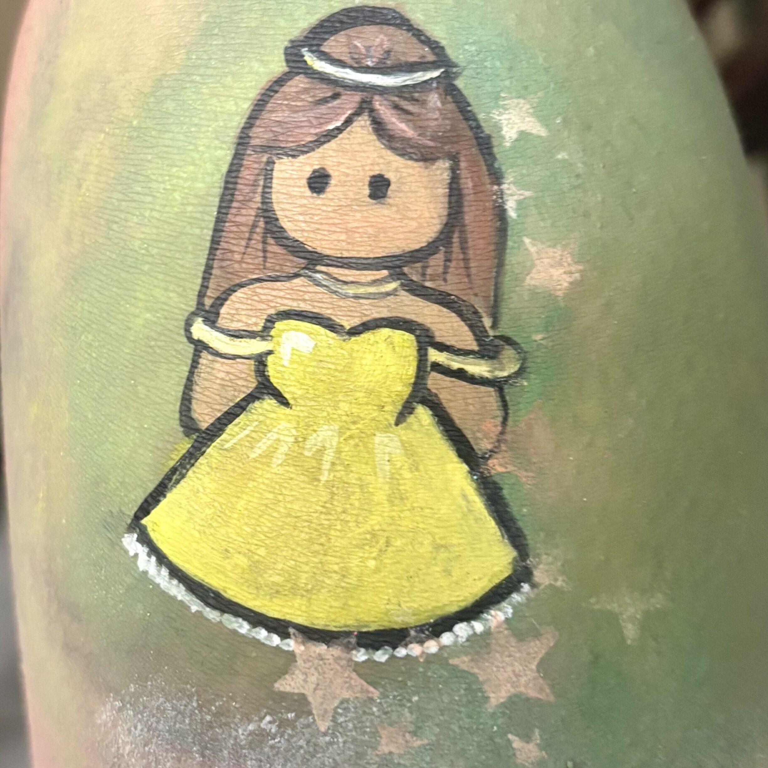 "Face painting of a cartoon princess in a yellow dress, set against a green background."