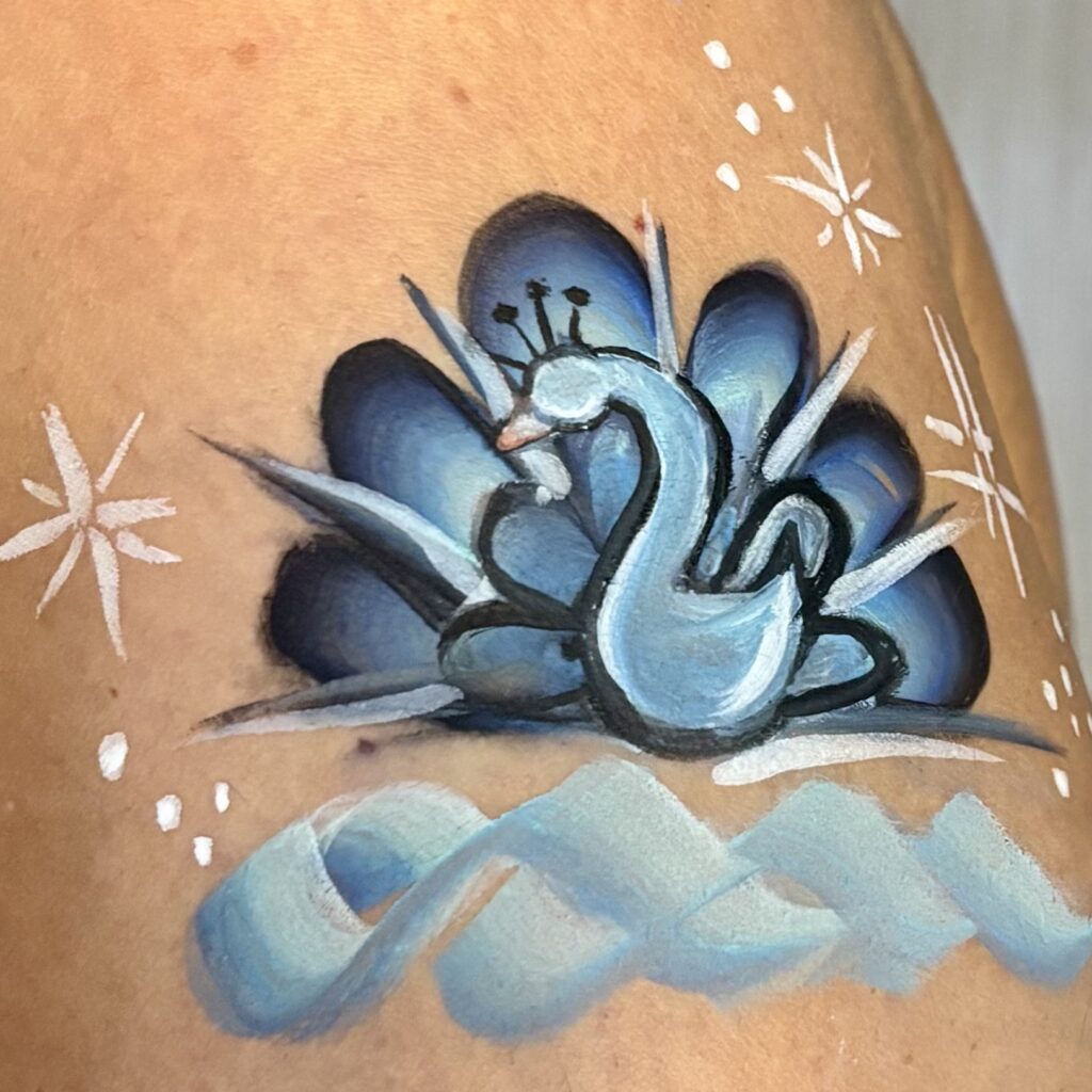 Face painting of a blue peacock design accented with white stars.