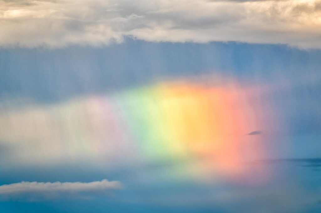 Rainbow and clouds in sky background.