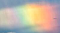 Rainbow and clouds in sky background.